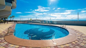Une piscine de forme circulaire, entourée d’une terrasse carrelée, et offrant une vue sur l’océan.