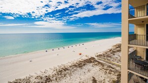 A beach view from a balcony with a clear sky and ocean.