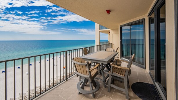 A balcony with a table and chairs overlooking a beach.