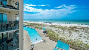 A hotel with a pool, beach view, and multiple balconies.
