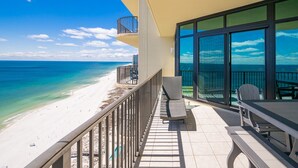 Ein Balkon mit Blick auf einen Strand und das Meer, inklusive Tisch und Stühlen.