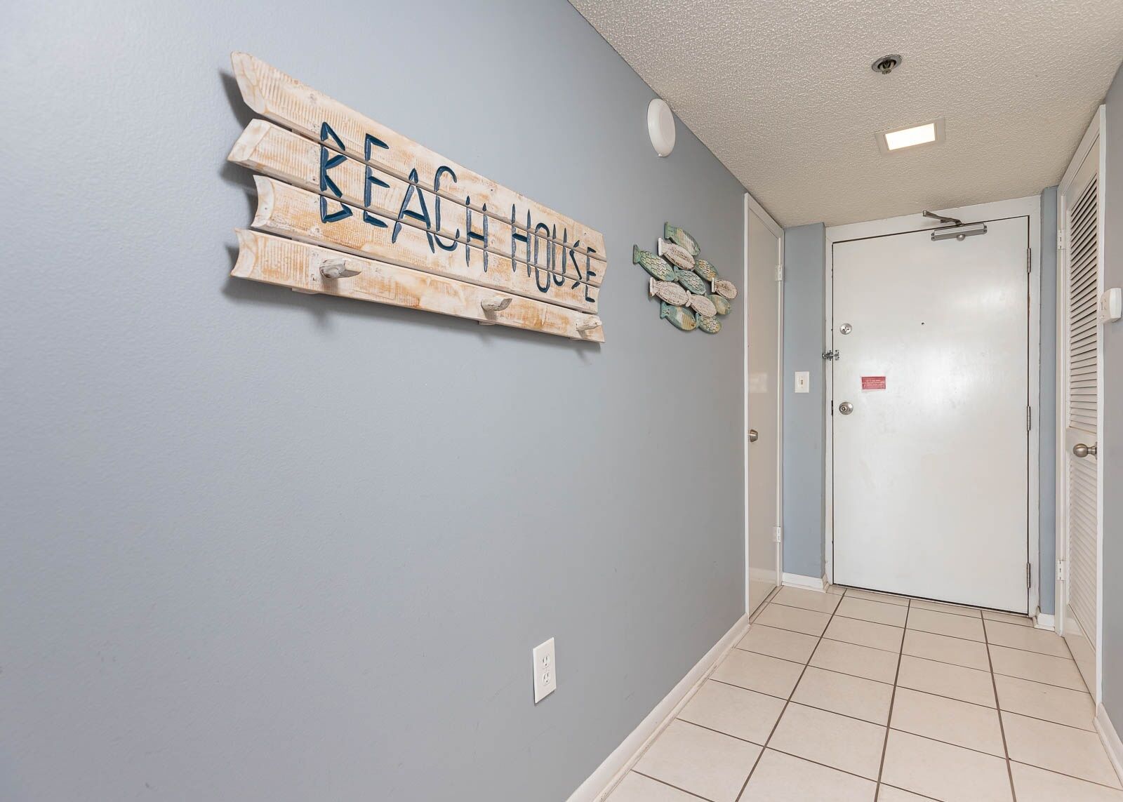 A hallway with a sign reading "BEACH HOUSE" and a door with a security lock.