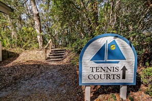 A sign for Tennis Courts with a sailboat symbol and an upward arrow.