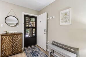 A hallway with a patterned cabinet, a door, a welcome mat, and a framed map on the wall. - 5d Amelia Landings 2 Bedroom Condo by RedAwning (Fernandina Beach)