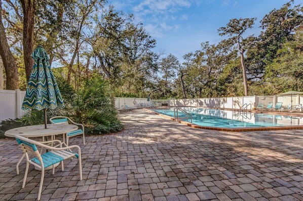 An outdoor swimming pool area with lounge chairs and a table.