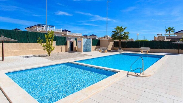 A swimming pool area with two pools, lounge chairs, and a small palm tree. - CH Casa Clementina Rojales (Rojales)