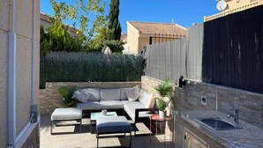 A patio with a sofa, ottoman, and a small table, a sink, and a potted plant. - CH Casa Clementina Rojales (Rojales)