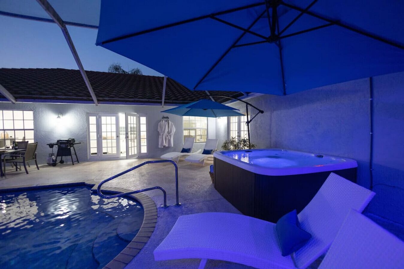 Una piscina interior amb un banyera d'hidromassatge, gandules i una zona de pati coberta.