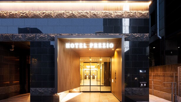 Entrada de hotel de diseño moderno, con fachada de piedra y un cartel que dice "HOTEL PRIZIO".