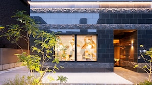 Un edificio moderno con fachada de piedra, amplias ventanas y un jardín bien cuidado.