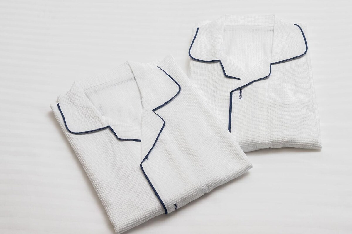 Dos camisas blancas bien dobladas con ribete azul.