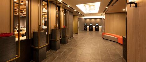 A modern hotel lobby with a reception desk, seating area, and a view of the reception counter.