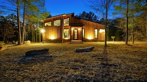 A modern wooden cabin with large windows, a front door, and a well-lit interior. - These Are The Days | Luxury Hochatown Cabin with Hot Tub, Grill & Pet-Friendly Comfort (Hochatown)