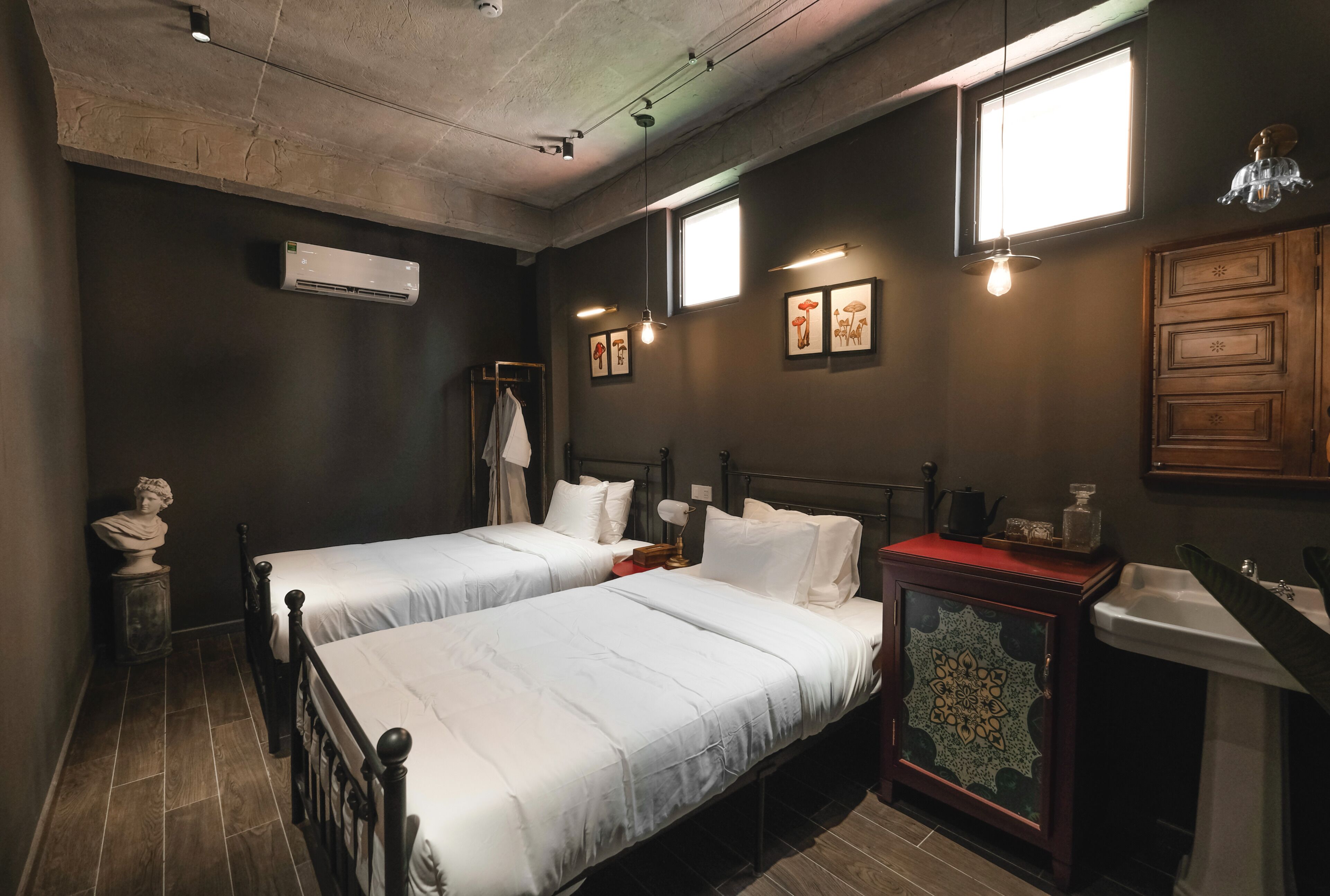 Una habitación con dos camas, un lavamanos y un mueble decorativo.