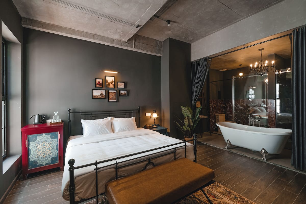 Un dormitorio moderno con una cama grande, un armario rojo, una bañera y un espejo amplio.