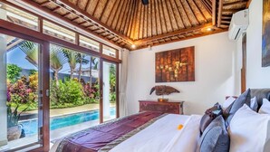 A bedroom with a large bed, a view of a swimming pool, and a ceiling fan.