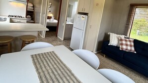 A compact RV-style accommodation with a kitchenette, a dining area, and a sofa with a view. - Wilsons Prom Holiday Park (Yanakie)