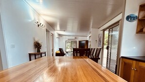 A spacious dining area with a long wooden table, chairs, and a television. - Wilsons Prom Holiday Park (Yanakie)