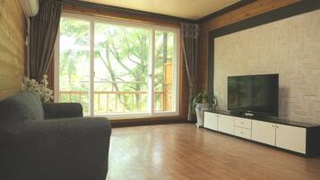 A living room with a large window, a flat-screen TV, and a grey sofa.
