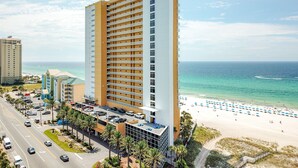 Un hôtel de grande hauteur doté de nombreux balcons offrant une vue sur une plage et l’océan.