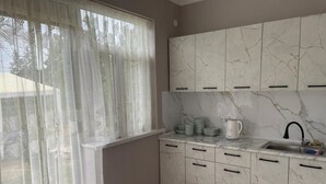 A kitchen with marble cabinets, a sink, and a window with sheer curtains.