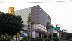 Un grand bâtiment avec une enseigne jaune et blanche bien visible, un panneau de signalisation vert indiquant les directions, et le logo de Cinepolis.
