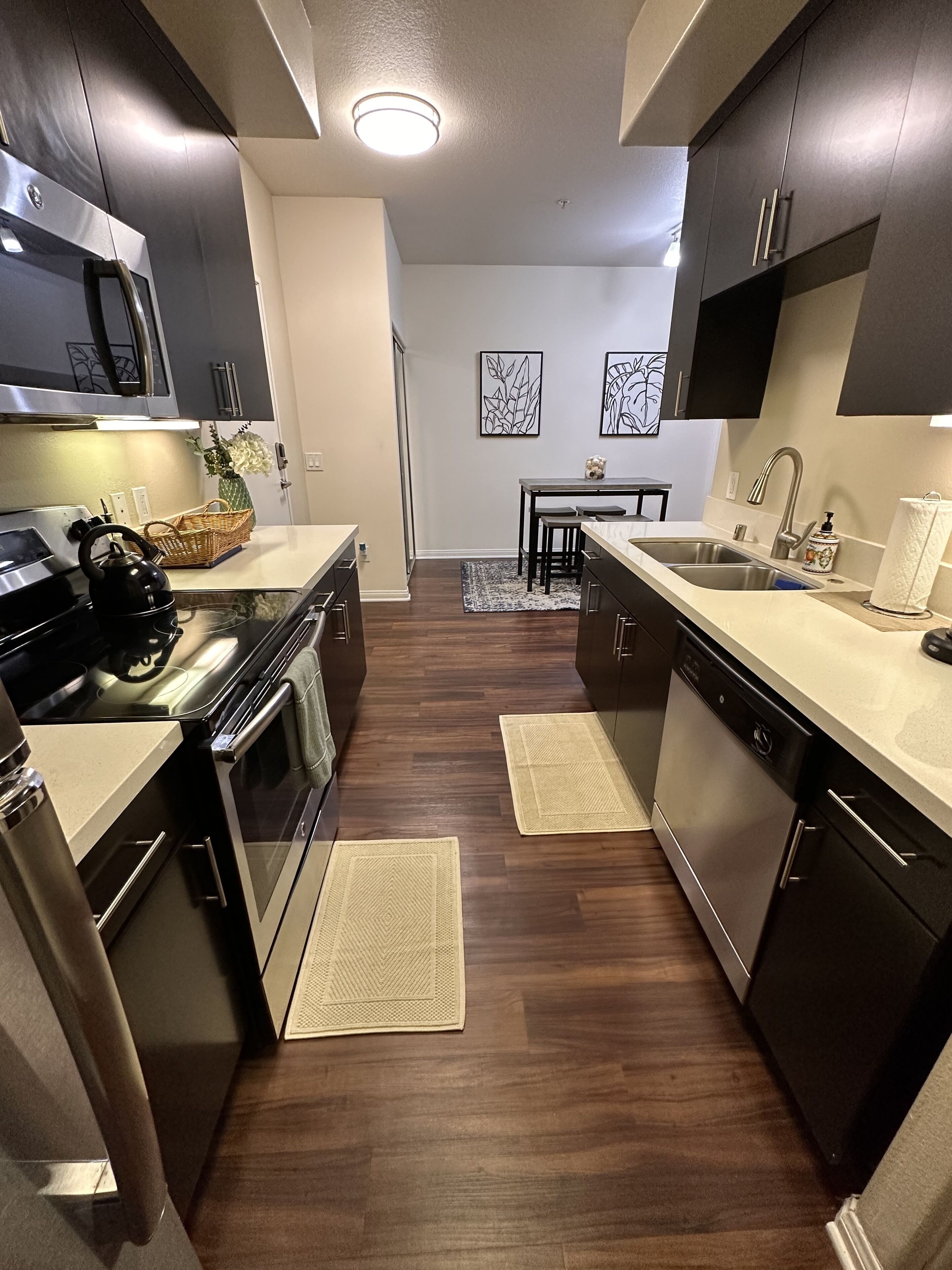 Una cocina moderna con armarios oscuros, electrodomésticos de acero inoxidable y una isla central.