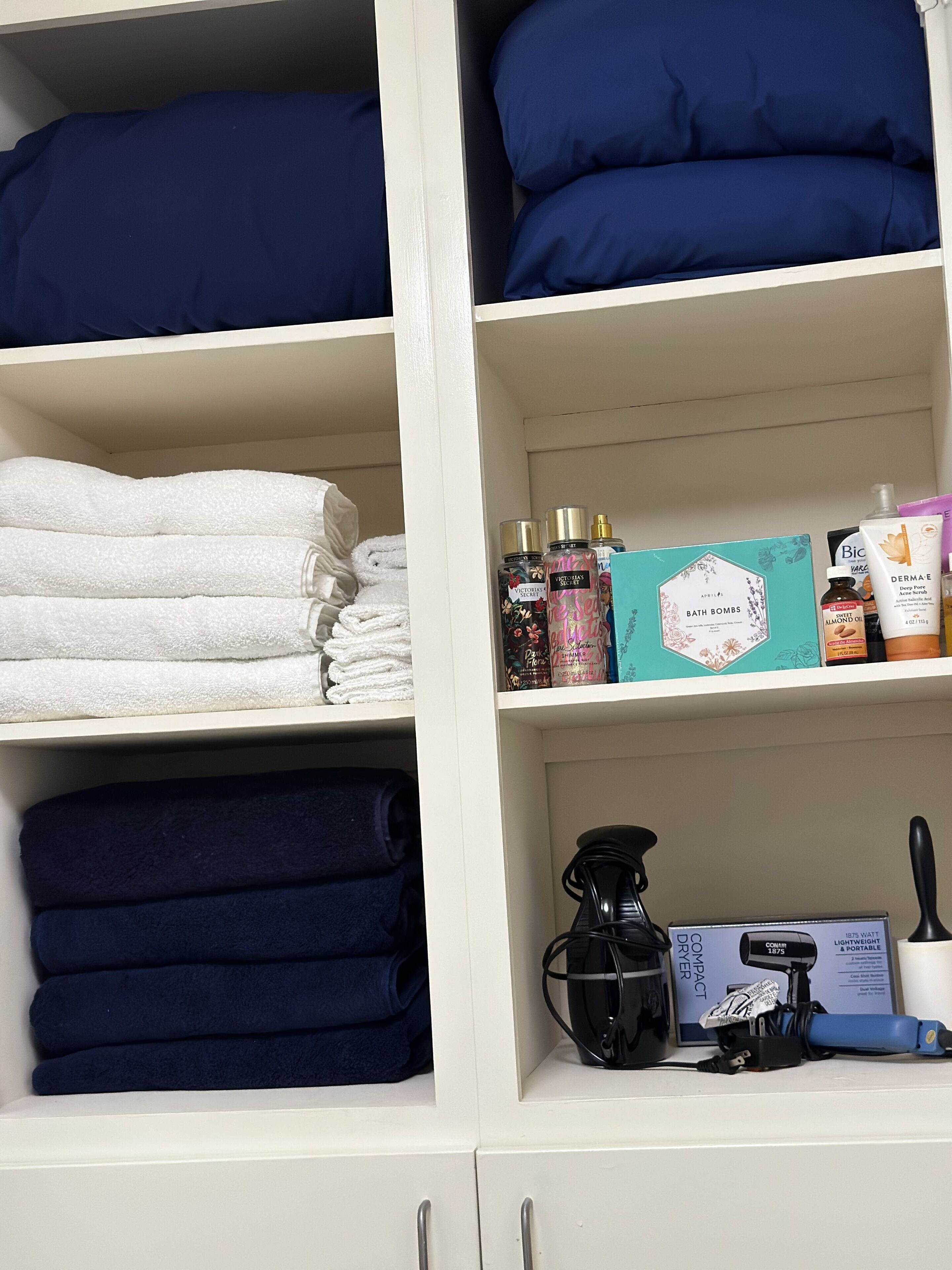 A neatly organized storage unit with folded towels, a coffee maker, and various toiletries.