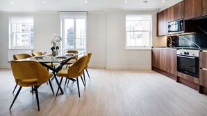 Eine moderne Küche mit Essbereich, ausgestattet mit einem großen Tisch mit Stühlen, Holzschränken und einer eingebauten Mikrowelle.