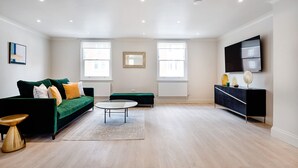 Ein modernes Wohnzimmer mit einem grünen Sofa, einem runden Couchtisch und einer schwarzen TV-Konsole.