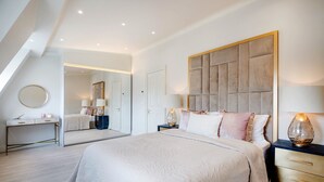 Ein modernes Schlafzimmer mit einem großen Bett, Nachttischen, einem Spiegel und einem Schreibtisch.
