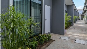 Een modern gebouw met een glazen deur, een betonnen pad en potplanten.