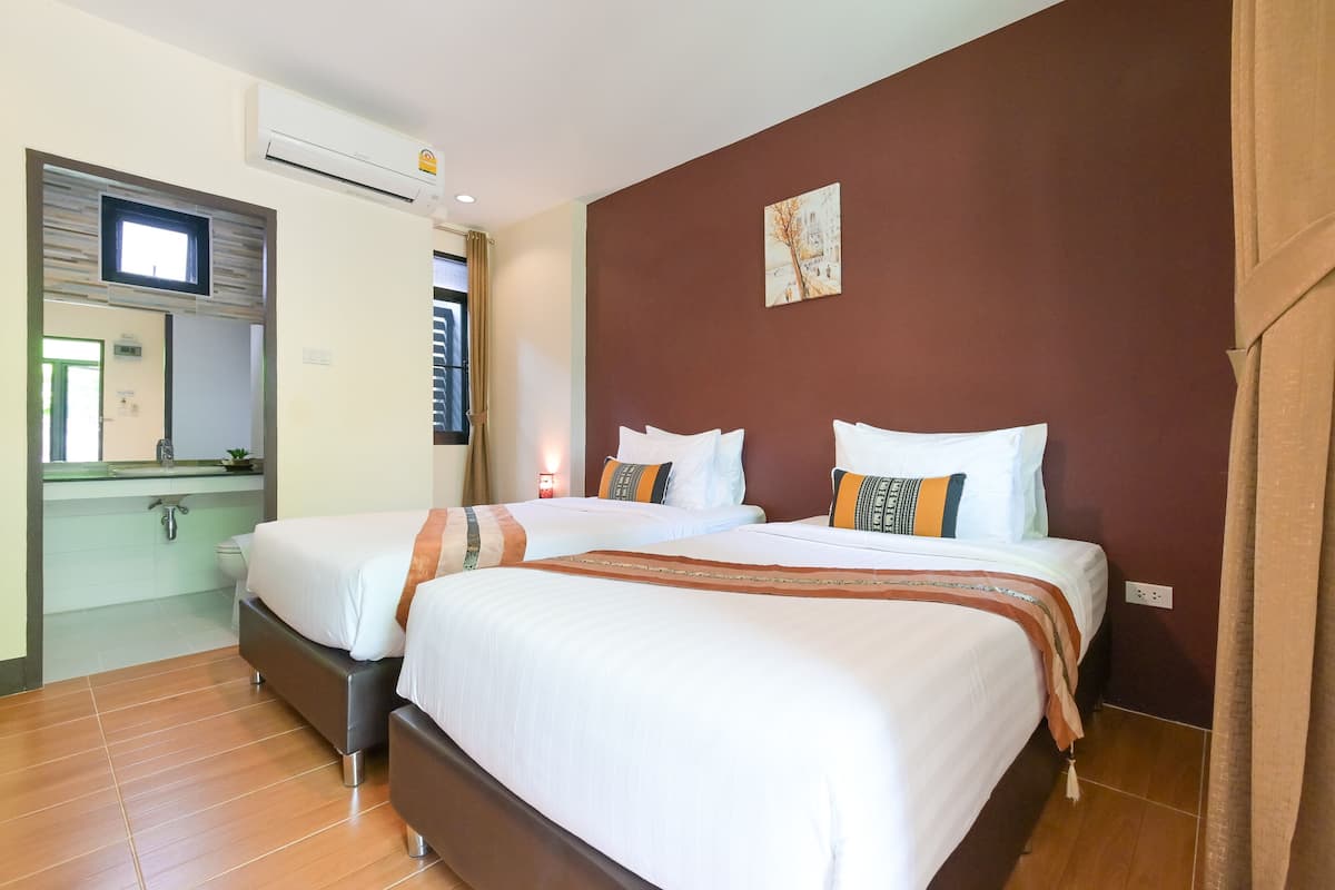 Een hotelkamer met twee bedden, een badkamer en een raam.