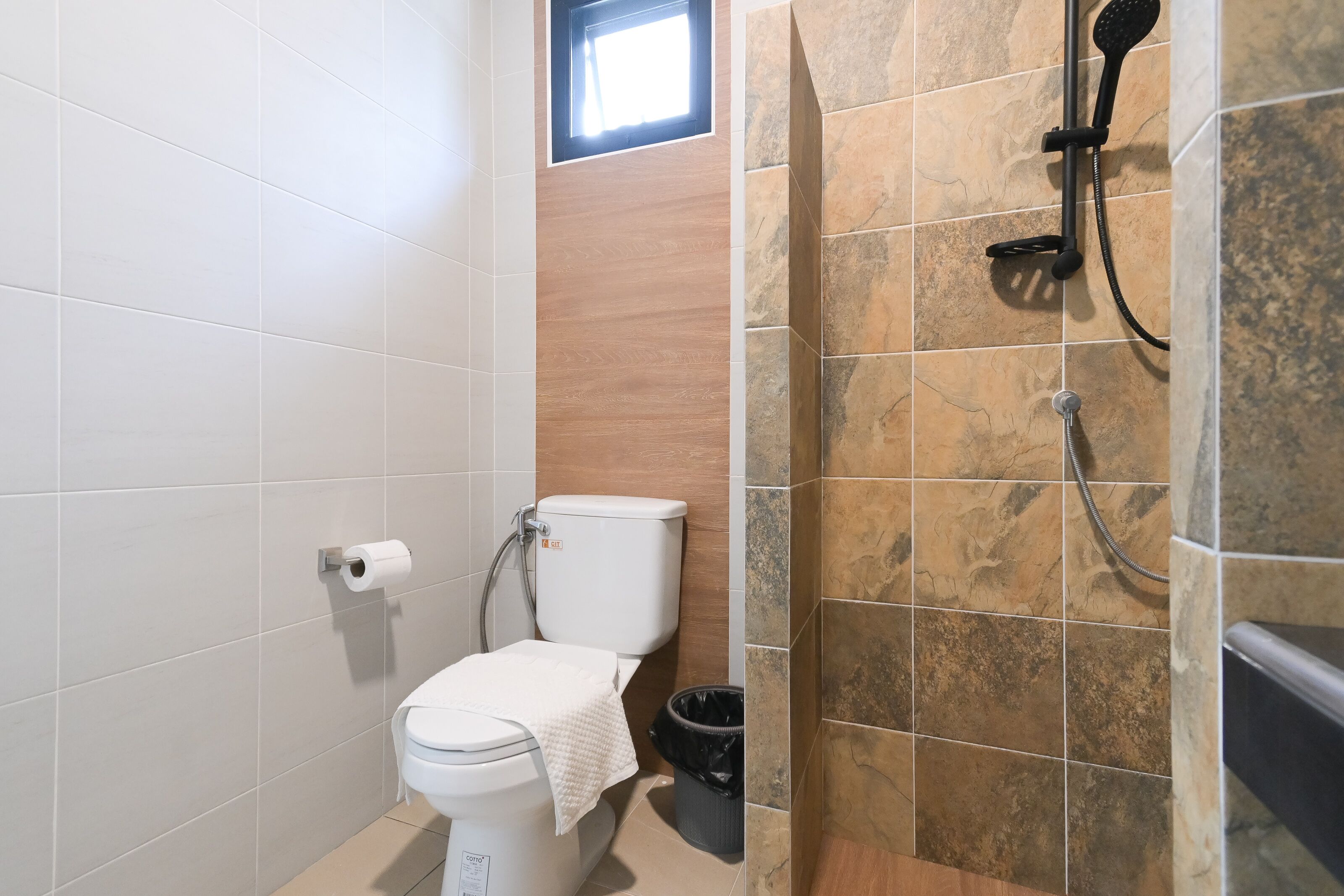 Un bagno con il water, una doccia e una finestra.