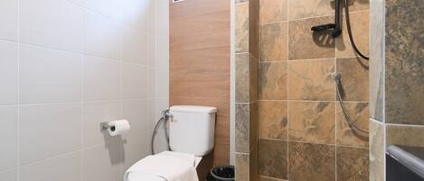 A bathroom with a toilet, a shower, and a window.