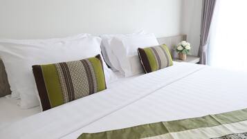 A neatly made bed with white linens and two decorative pillows with green and brown patterns.
