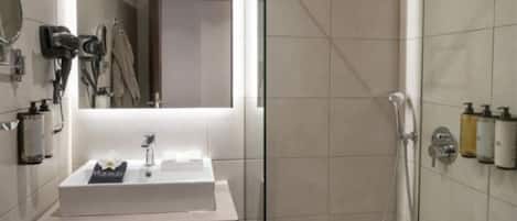 A modern bathroom with a glass-enclosed shower, a vanity with a mirror, and a sink.