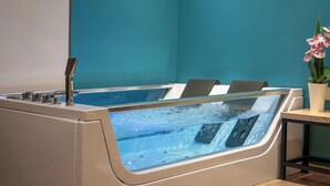 A spa area with a hot tub, seating, and a potted orchid. - IRA-HPA Hotel (Kalamata)