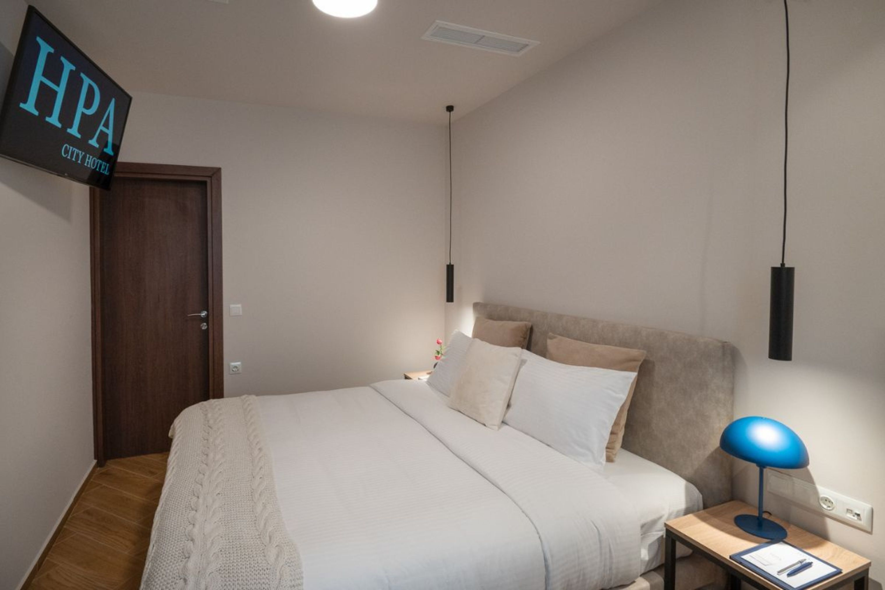 Una habitación de hotel con cama, mesita de noche, lámpara y un cartel en la pared.