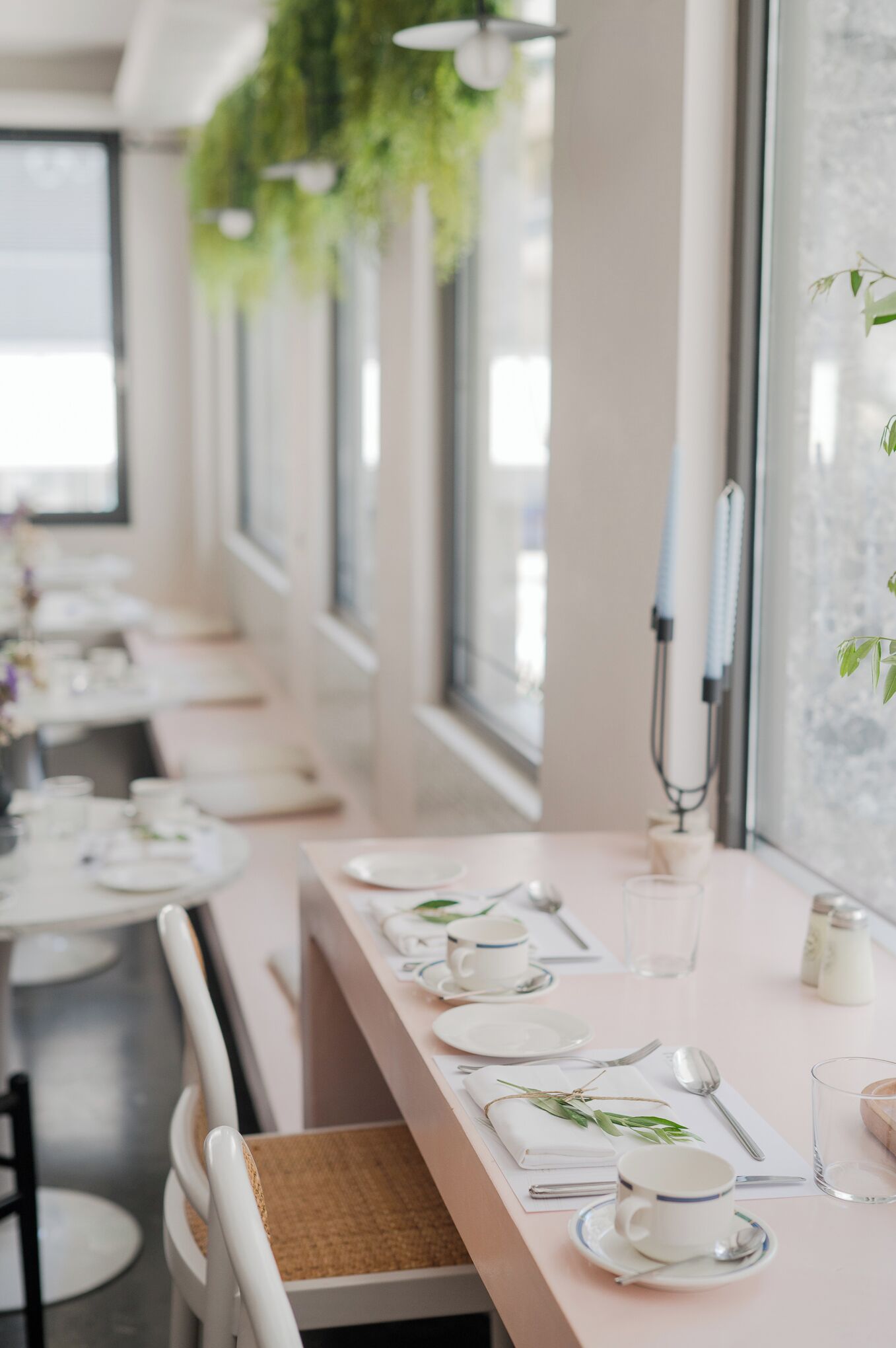 A dining area with tables set for a meal, featuring white tablecloths, plates, cups, and cutlery.