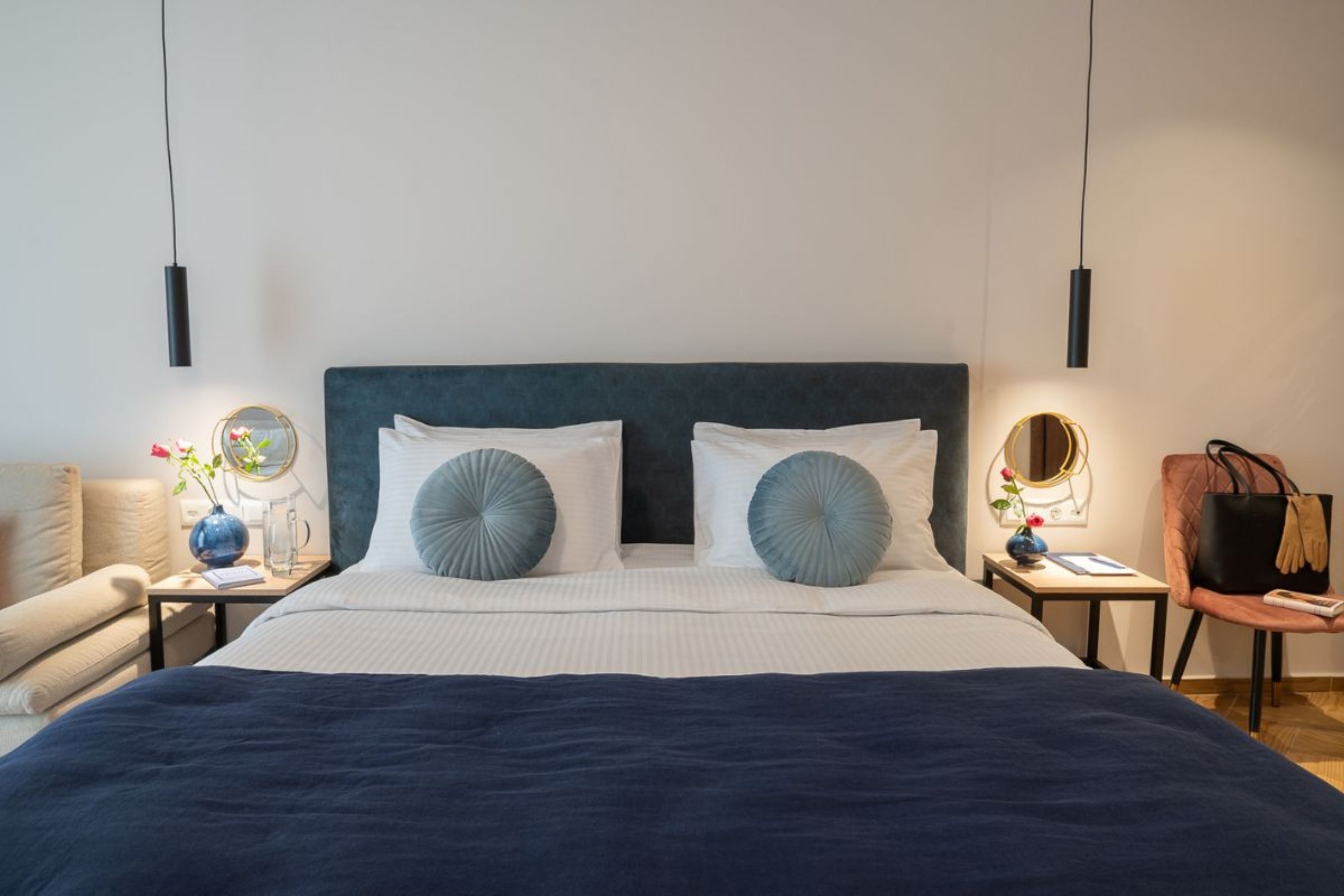 Een keurig opgemaakt slaapkamer met een groot bed, twee nachtkastjes, een stoel en een spiegel.