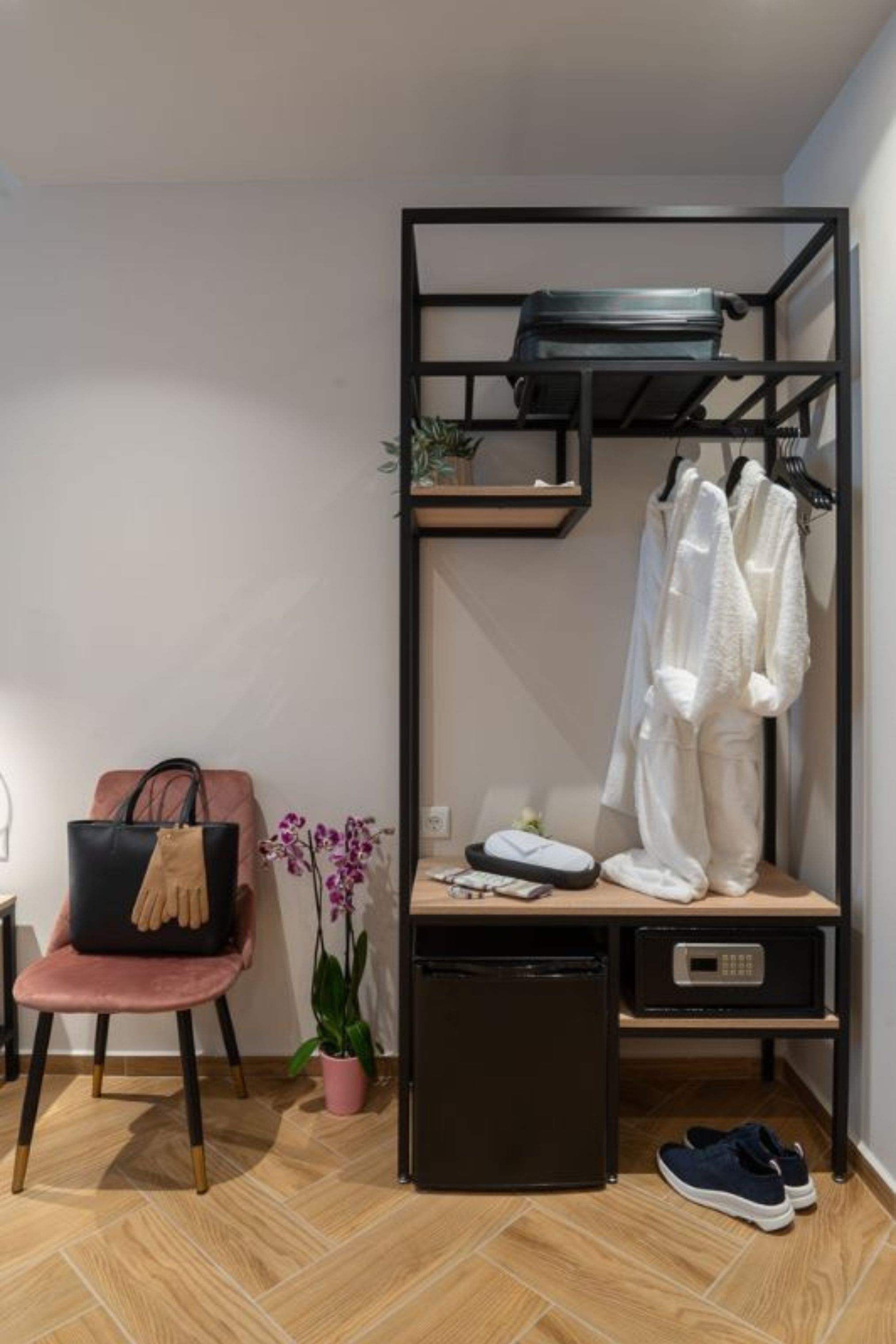 Une pièce de taille modeste, dotée d’une armoire intégrée, d’un petit bureau, d’une chaise et d’une plante en pot.