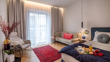 Una habitación de hotel moderna con cama, sofá y una pequeña mesa con un florero y flores.