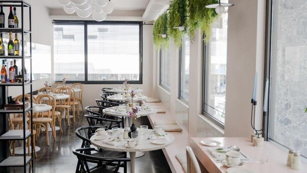 A restaurant with round tables, chairs, and a long counter with a bar area. - IRA-HPA Hotel (Kalamata)