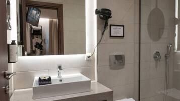 Un baño moderno con un espejo grande, un lavamanos, un inodoro y una zona de ducha.