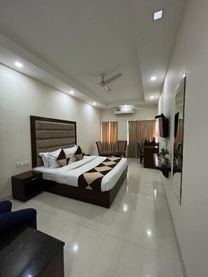 Quarto de hotel moderno com uma cama grande, uma escrivaninha e uma televisão.