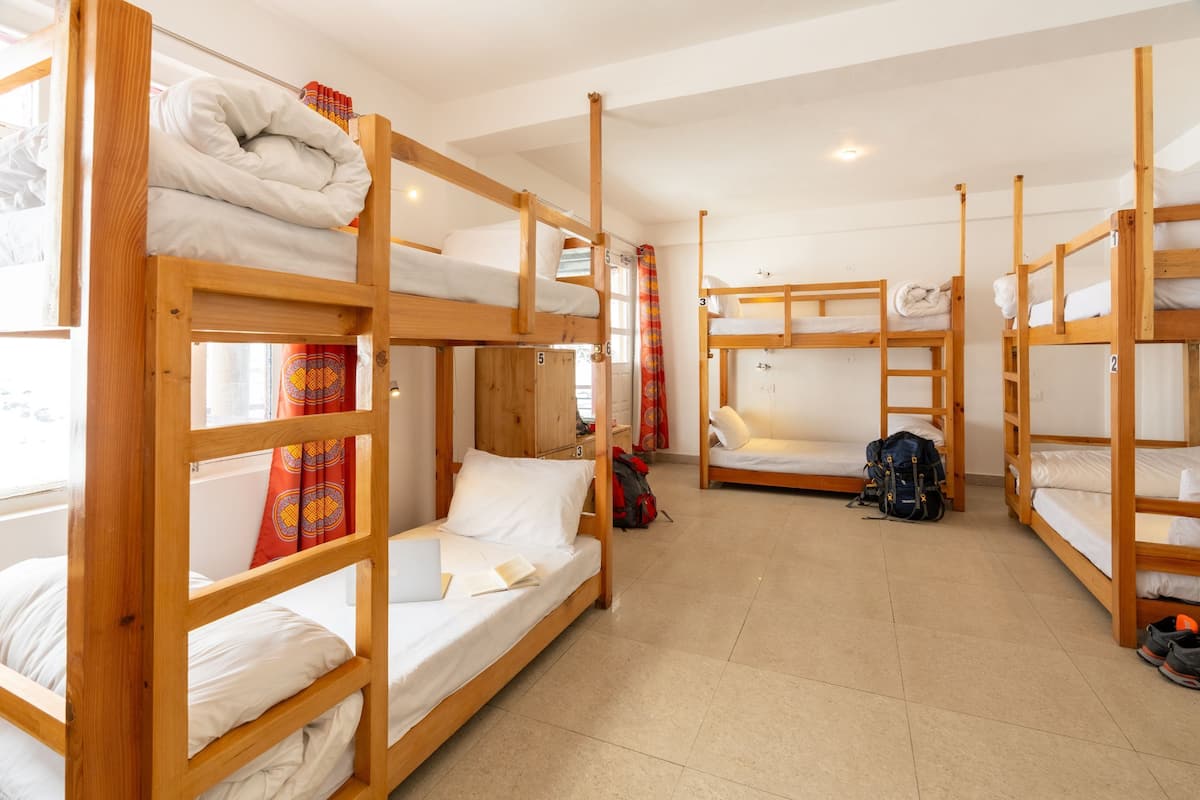 A dormitory room with bunk beds, a desk, and a chair.
