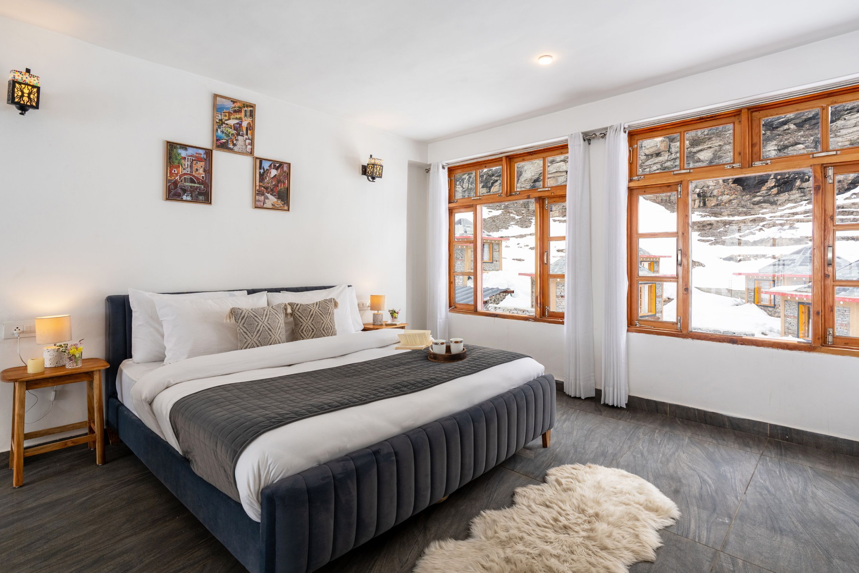 Un dormitorio con una cama grande, cabecera de madera y vistas a una montaña nevada.