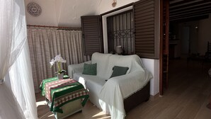 En hyggelig stue med en sofa, et lille bord med dug og en hængende lampe.
