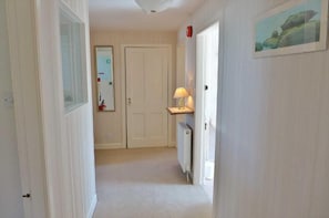 A hallway with a radiator, a door, and a lamp on a shelf.
